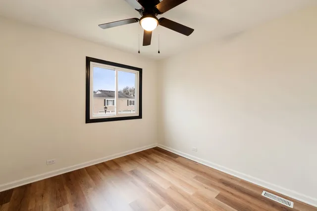 an empty room with a window and a ceiling fan