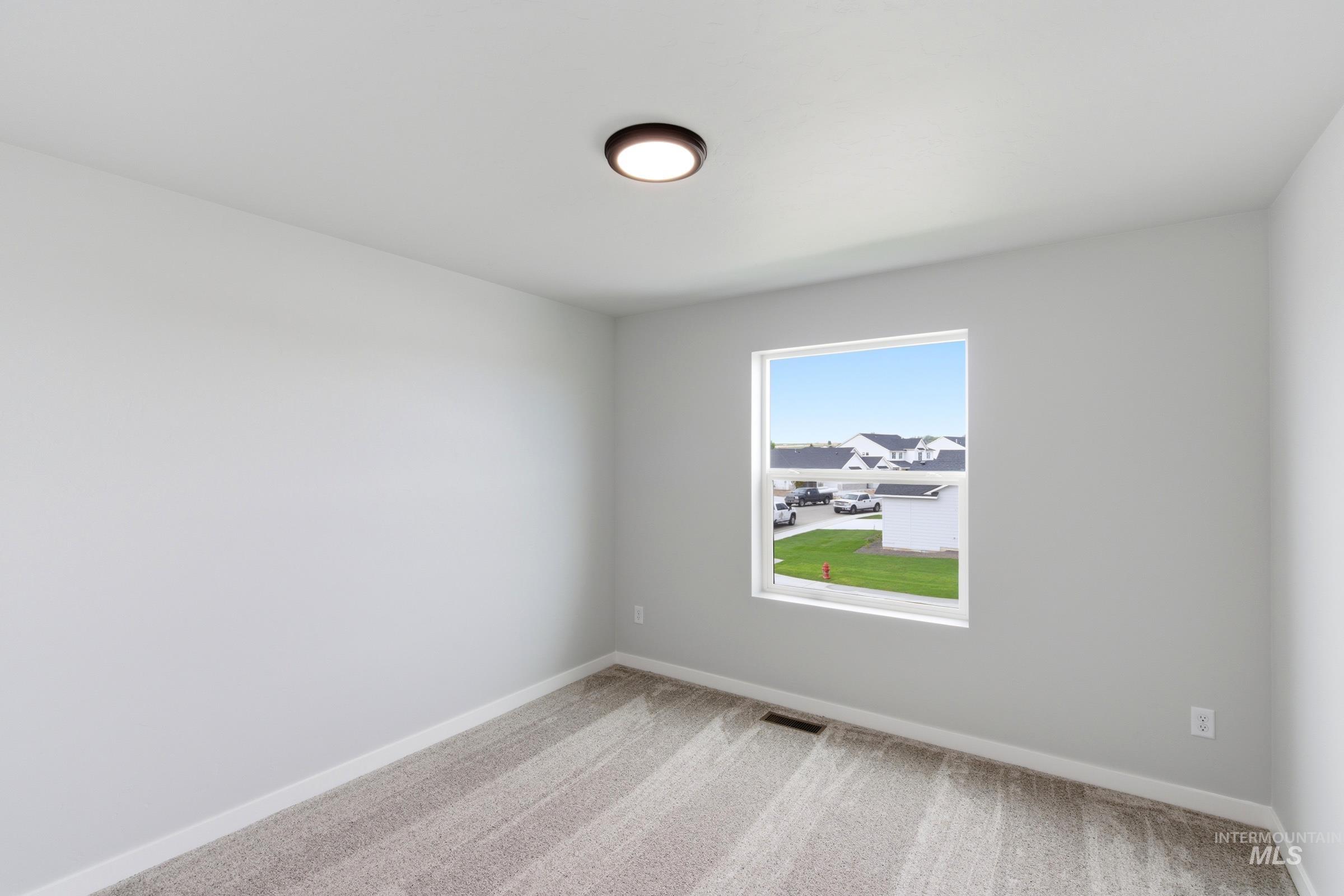 16558 Dunning Way Caldwell, ID 83607 - Photo 20 of 35 Neutral-toned room featuring a single window, overhead flush-mount lighting, light gray walls, and textured carpet flooring