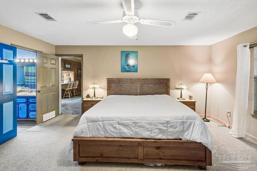 8938 Pioneer Road Holt, FL 32564 - Photo 19 of 44 a bedroom with a large bed and a chandelier