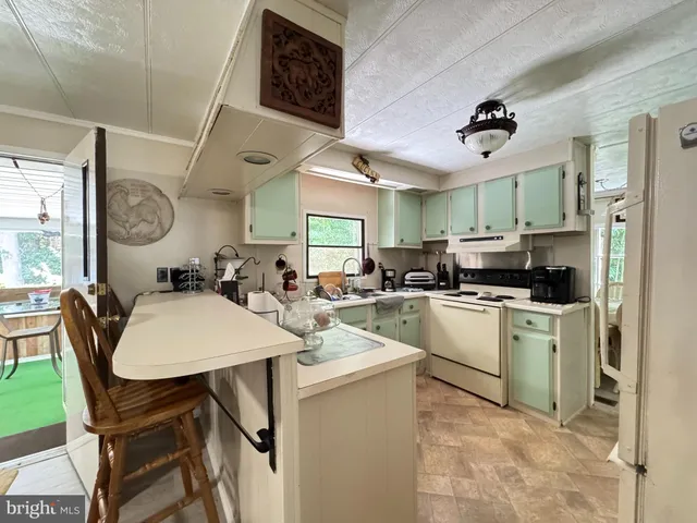 a kitchen with stainless steel appliances kitchen island granite countertop a sink a stove a refrigerator cabinets and chairs