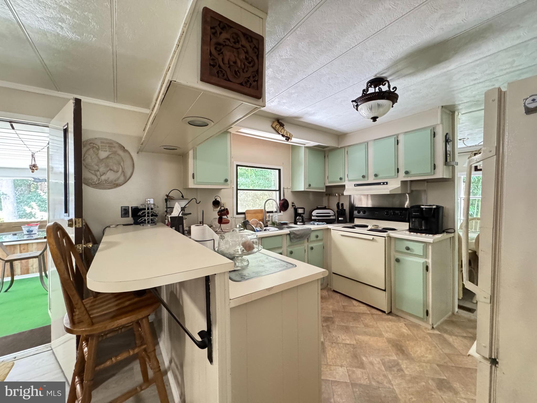 34118 Pinewood Circle, Unit 11080 Lewes, DE 19958 - Photo 11 of 22 a kitchen with stainless steel appliances kitchen island granite countertop a sink a stove a refrigerator cabinets and chairs