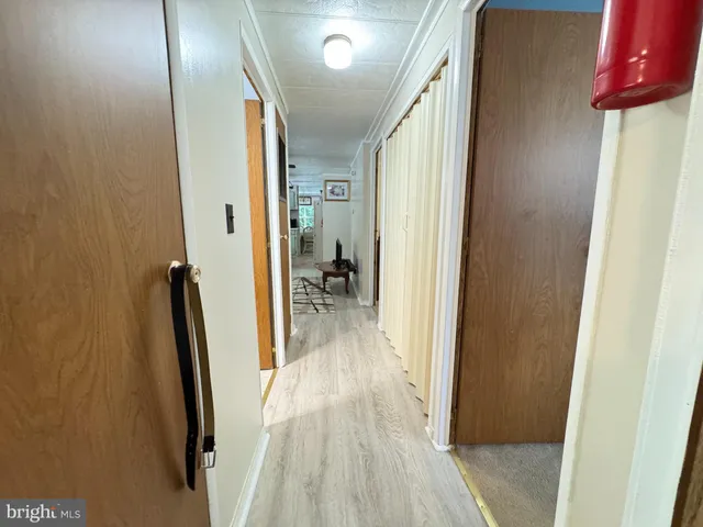 a view of a hallway with wooden floor and a bathroom