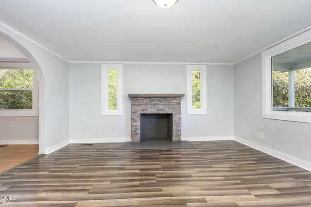 a view of a livingroom with a fireplace window and wooden floor