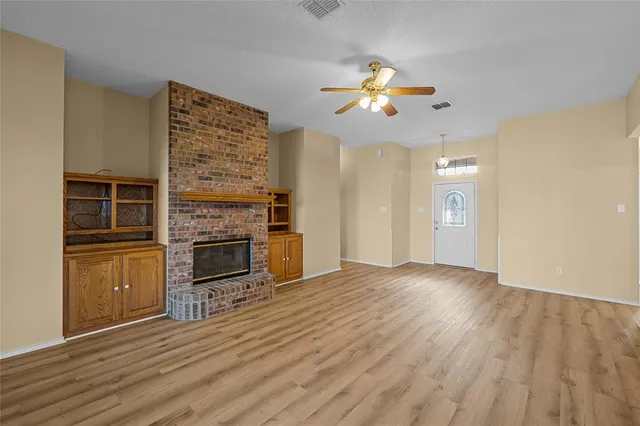a view of a livingroom with a fireplace a ceiling fan and wooden floor