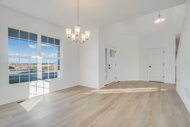 a view of wooden floor chandelier and windows in a room
