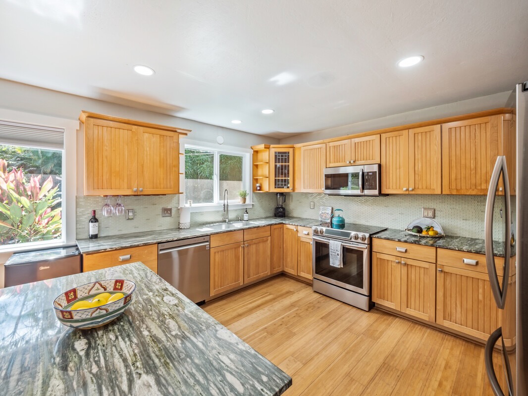 84-5085 Painted Church Road Honaunau, HI 96704 - Photo 3 of 30 a kitchen with stainless steel appliances granite countertop wooden cabinets a stove a sink a dining table and chairs