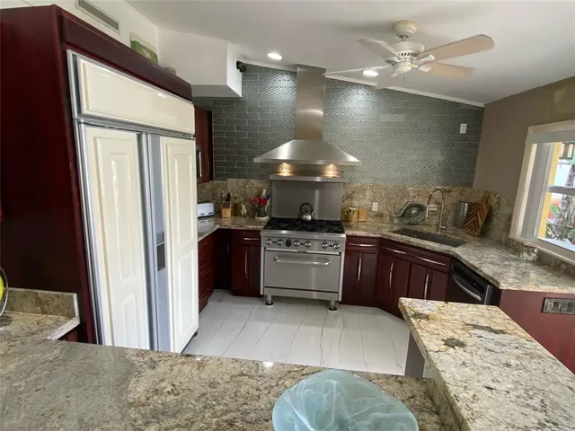 a kitchen with stainless steel appliances kitchen island granite countertop a refrigerator stove and sink