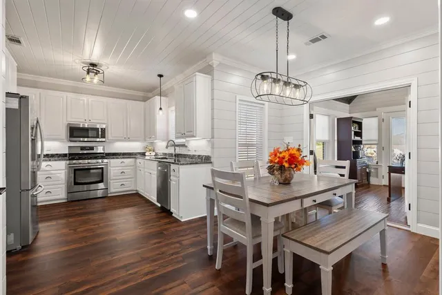 a kitchen with stainless steel appliances kitchen island granite countertop a stove refrigerator dining table and chairs