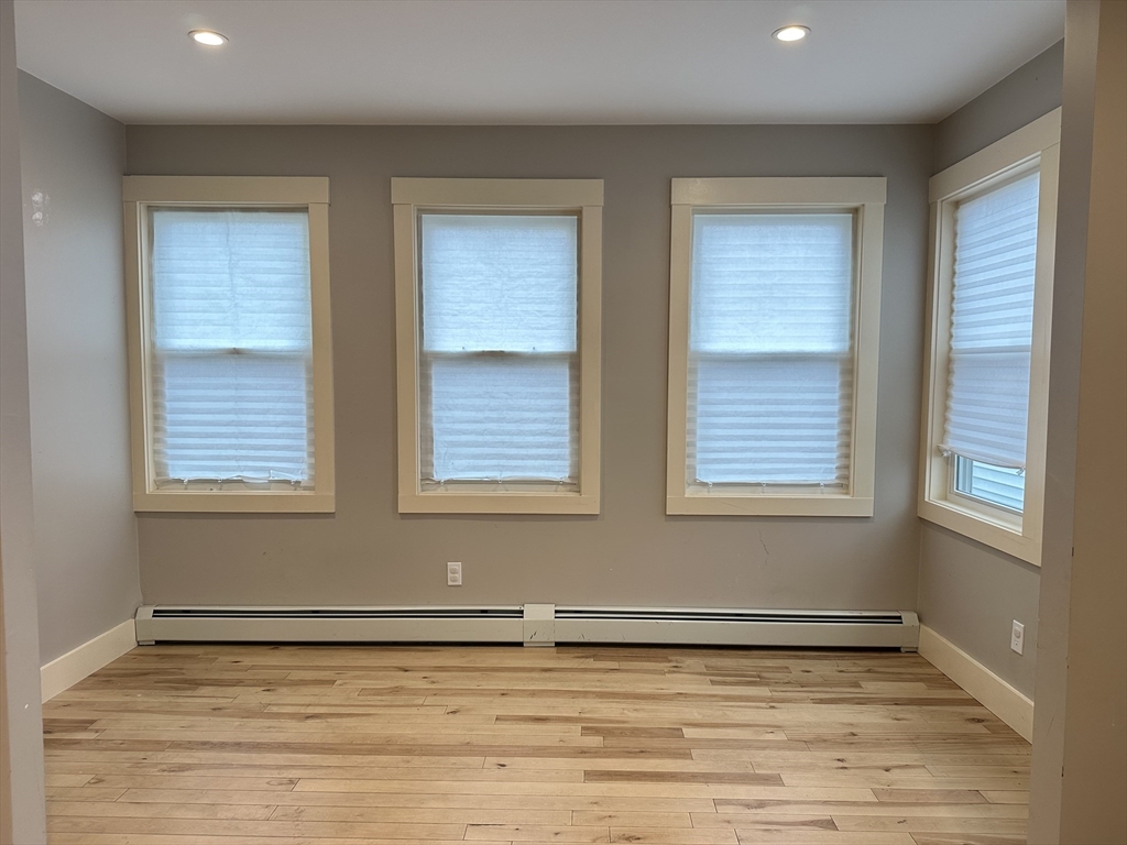 39 Snow Street, Unit SINGLE Boston, MA 02135 - Photo 11 of 28 a view of an empty room with a window and wooden floor