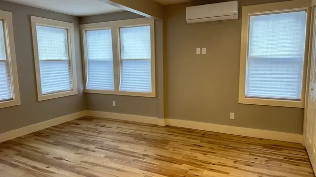 a view of an empty room with window and wooden floor