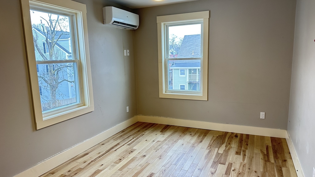 39 Snow Street, Unit SINGLE Boston, MA 02135 - Photo 25 of 28 a view of an empty room with wooden floor and a window