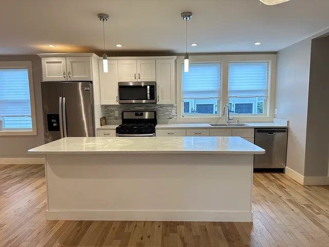 a kitchen with stainless steel appliances a refrigerator a sink a stove a microwave and wooden floor