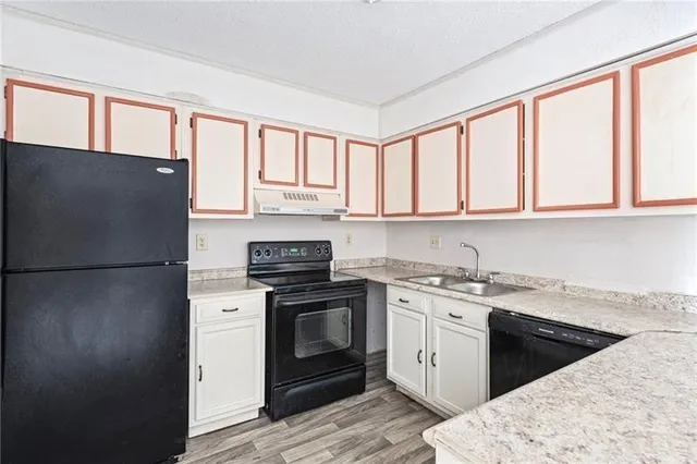 a kitchen with stainless steel appliances granite countertop grey cabinets a refrigerator a stove a sink and a window