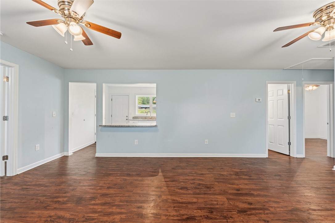 104 Leah Drive Pendleton, SC 29670 - Photo 5 of 23 This living space features warm hardwood flooring, a ceiling fan, and a convenient pass-through window to the kitchen.