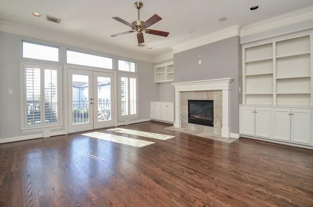 a view of an empty room with a fireplace and wooden floor