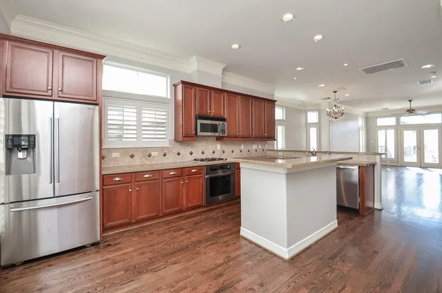 a kitchen with stainless steel appliances granite countertop a refrigerator a sink dishwasher a stove with wooden floors and cabinets