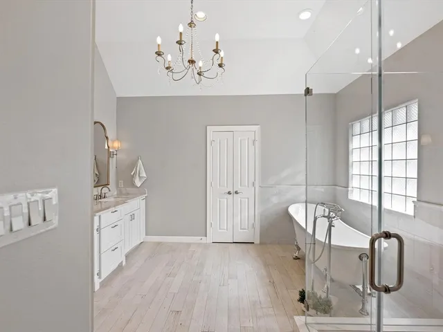 a spacious bathroom with a chandelier a sink and a window