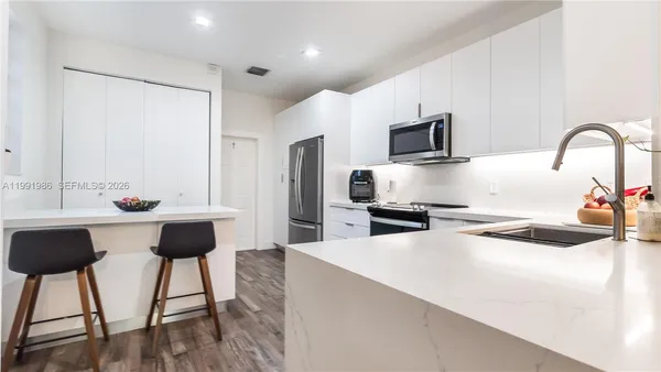 a kitchen with stainless steel appliances kitchen island a table and chairs in it