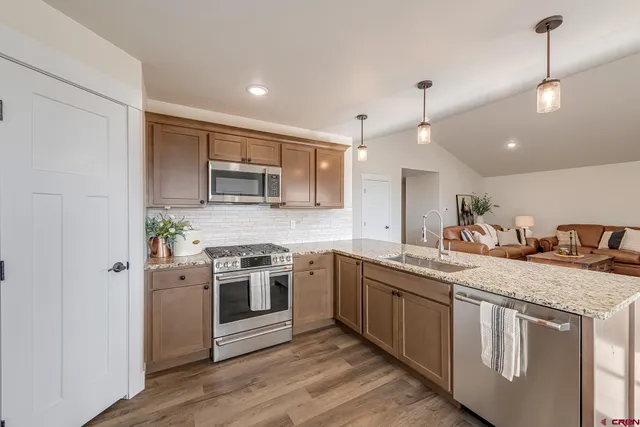 a kitchen with stainless steel appliances granite countertop a stove a sink and a refrigerator