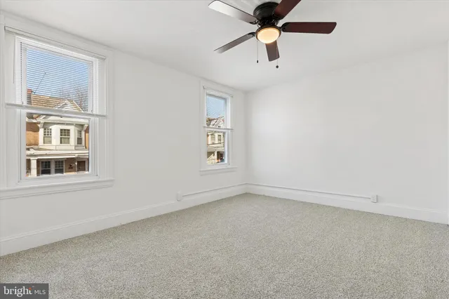 an empty room with a window and a fan