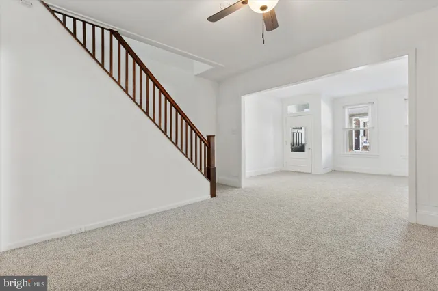 a view of an empty room with wooden floor and staircase