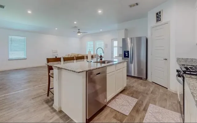 a kitchen with stainless steel appliances granite countertop a sink a stove a refrigerator and a oven