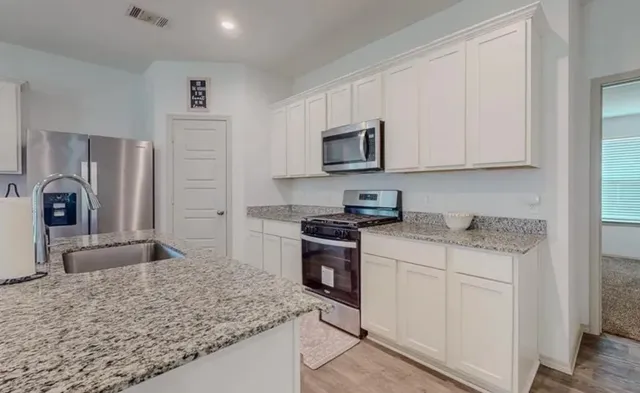 a kitchen with stainless steel appliances granite countertop a sink stove and microwave