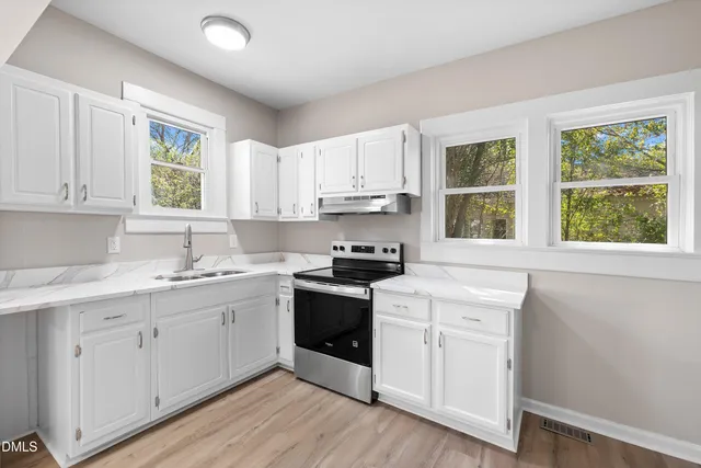 a kitchen with a sink cabinets wooden floor and a window