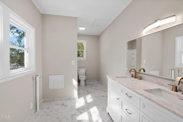 a bathroom with double vanity sink a mirror and a toilet