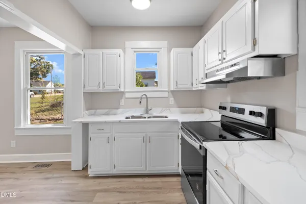 a kitchen with cabinets appliances a sink and a window