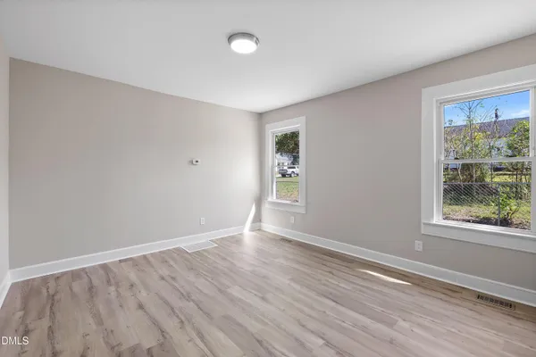 a view of an empty room with wooden floor and a window