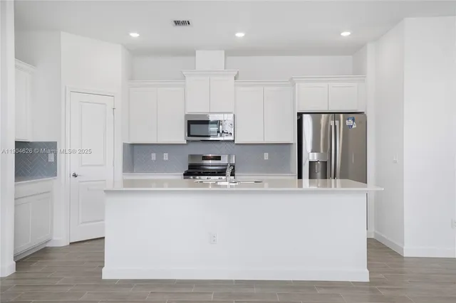 a view of kitchen with a sink refrigerator and a window
