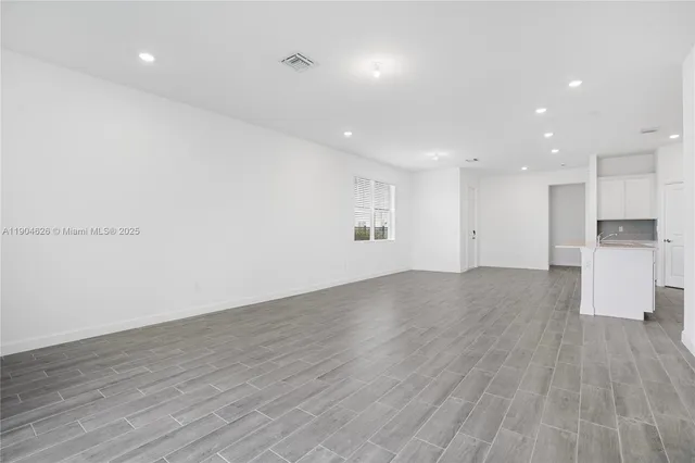 an empty room with wooden floor and window