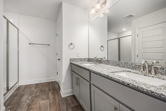 a bathroom with a granite countertop sink a mirror and shower