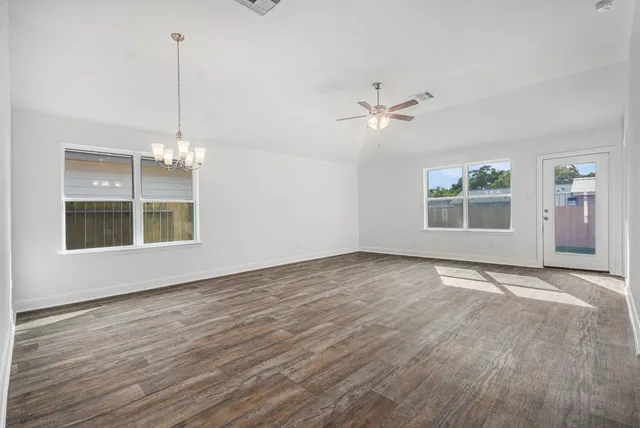 a view of an empty room with a window and wooden floor