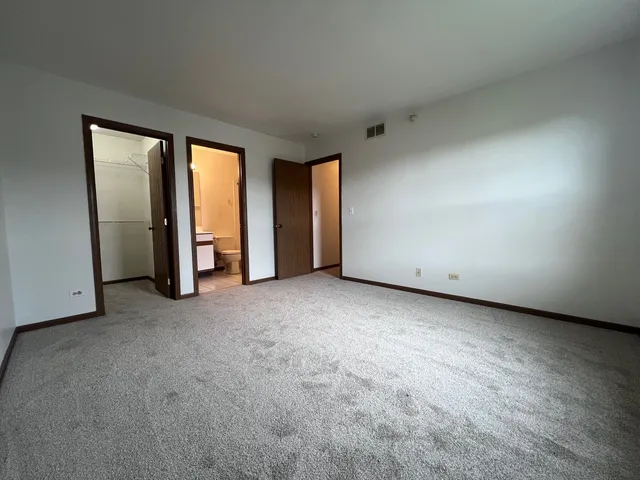 a view of an empty room with closet and a window