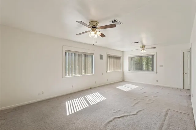 a view of an empty room with a ceiling fan and closet area