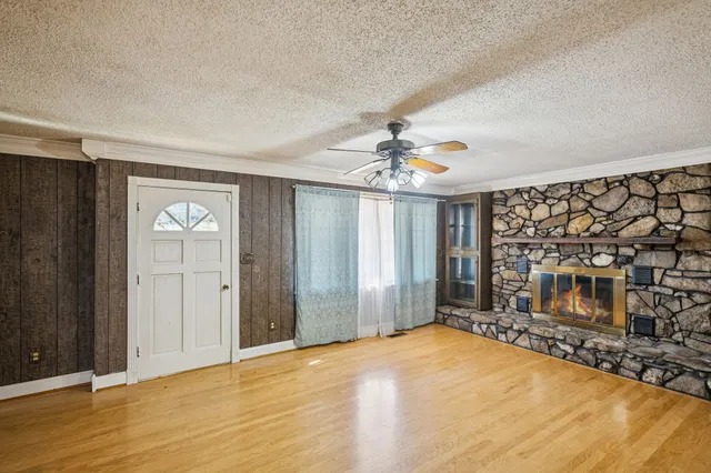 a view of an empty room with wooden floor and a fireplace