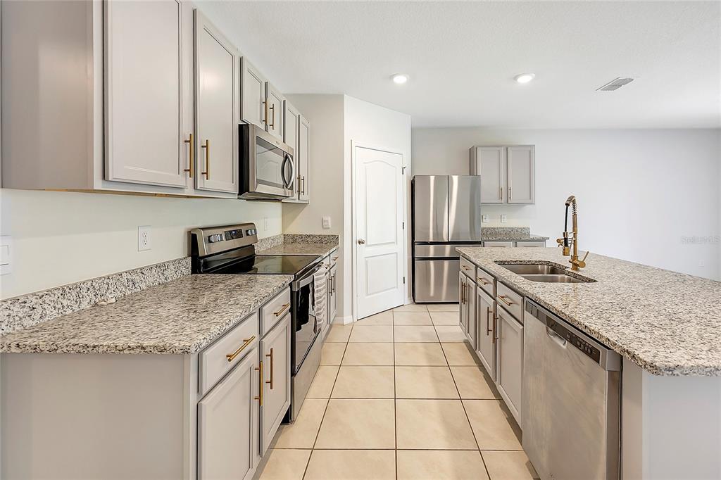 2726 Harmonia Hammock Road Harmony, FL 34773 - Photo 5 of 18 a kitchen with stainless steel appliances granite countertop a sink stove and refrigerator