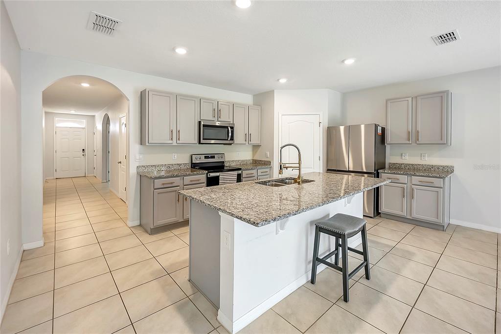 2726 Harmonia Hammock Road Harmony, FL 34773 - Photo 7 of 18 a kitchen with stainless steel appliances granite countertop a refrigerator and a stove top oven