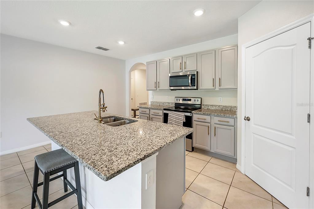 2726 Harmonia Hammock Road Harmony, FL 34773 - Photo 9 of 18 a kitchen with kitchen island granite countertop a stove a sink and a refrigerator