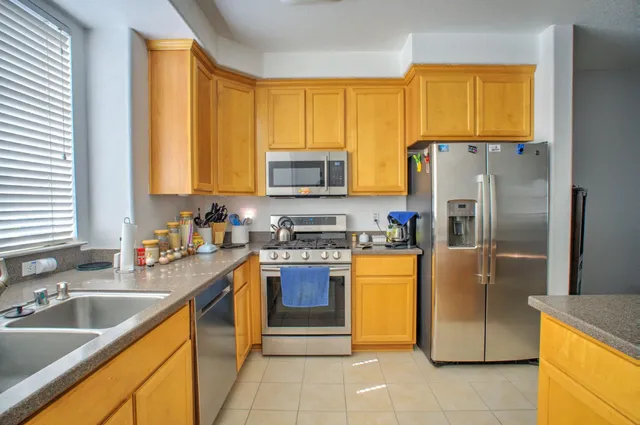 a kitchen with stainless steel appliances granite countertop a refrigerator a sink a stove a washer dryer and a window