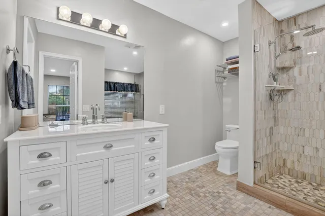 a bathroom with a granite countertop sink a toilet and a shower