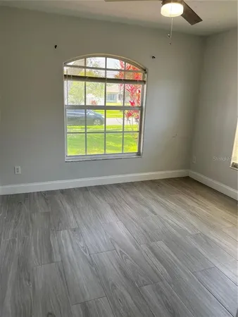 an empty room with wooden floor and windows