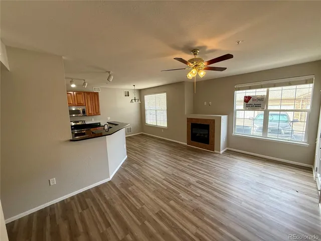 a view of kitchen and empty room with wooden floor and fan