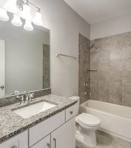 a bathroom with a granite countertop sink a toilet and bathtub