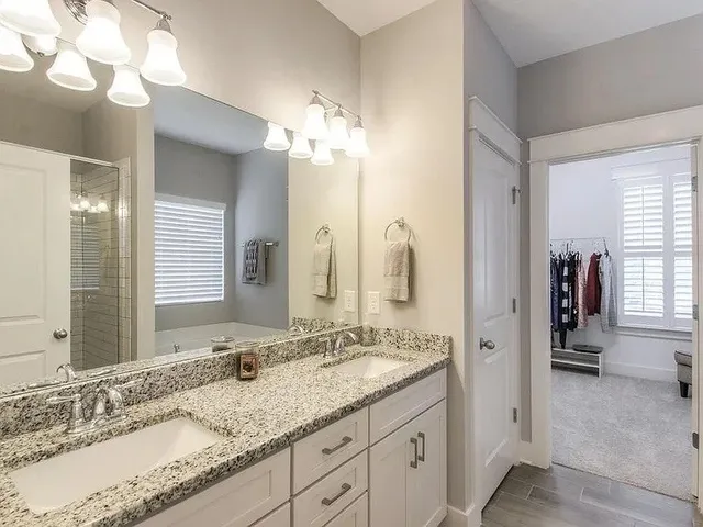 a bathroom with a granite countertop double vanity sink and a mirror
