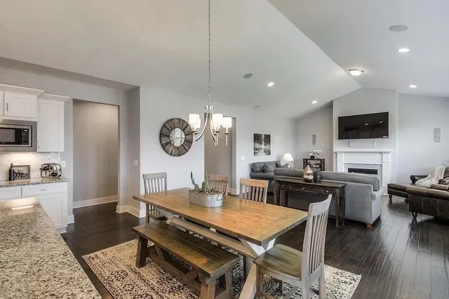 a dining hall with stainless steel appliances granite countertop a stove a sink a dining table and chairs with wooden floor