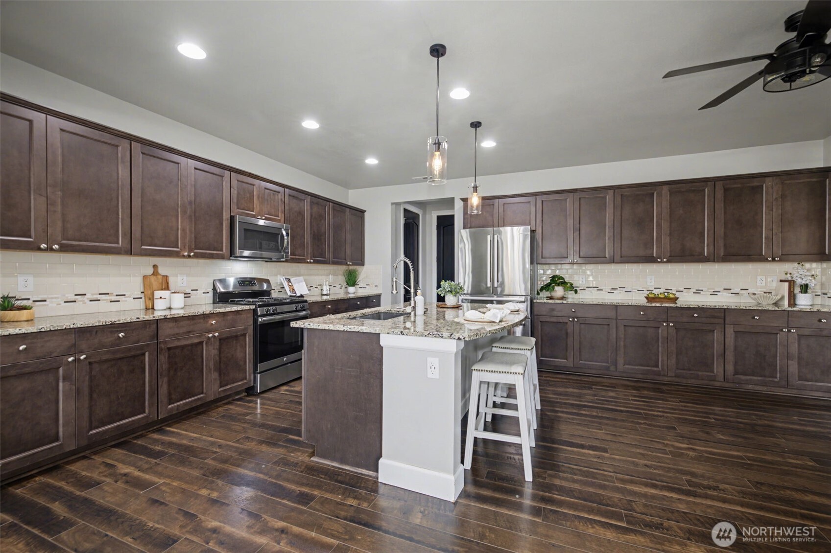 207 Fielding Street Northeast Orting, WA 98360 - Photo 11 of 37 a kitchen with kitchen island granite countertop wooden floors wooden cabinets and appliances