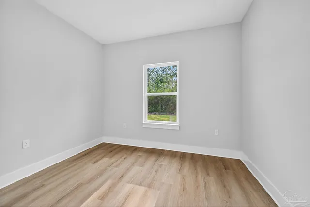 an empty room with wooden floor chandelier fan and windows